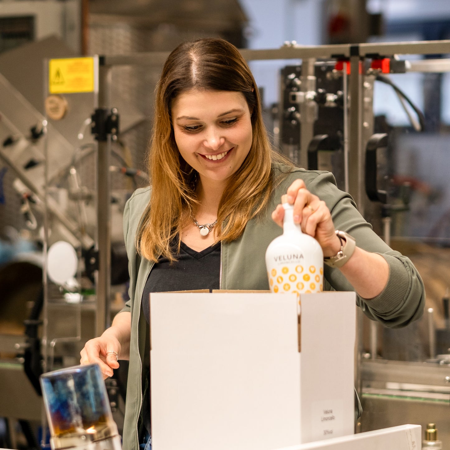 Die Gründerin Laura-Marie verpackt Veluna Limoncello in Kartons